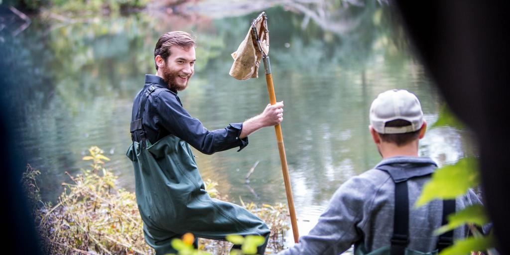 Biology student wading in stream